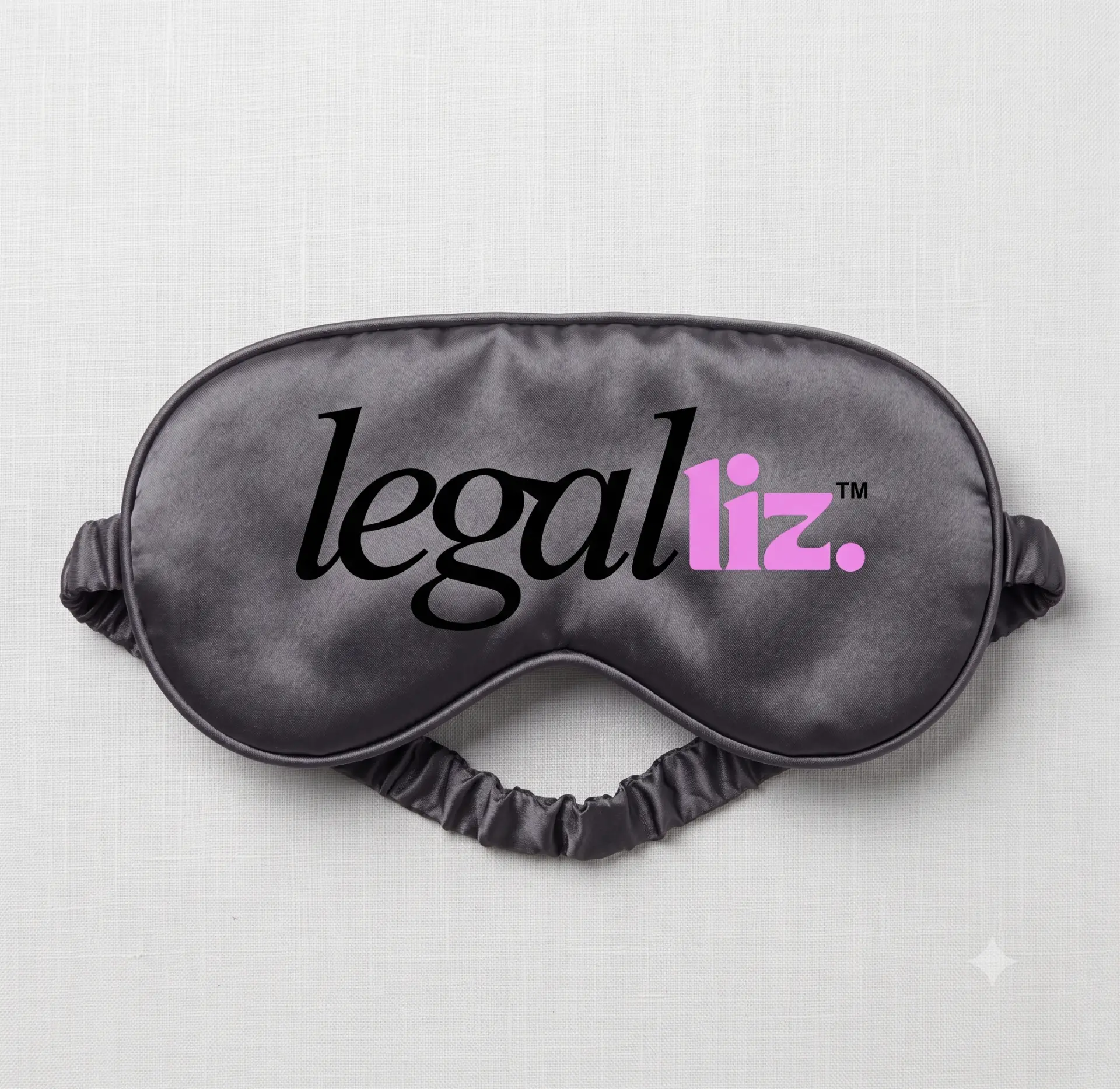 Grey satin sleep mask printed with the LegalLIZ logo in black and pink